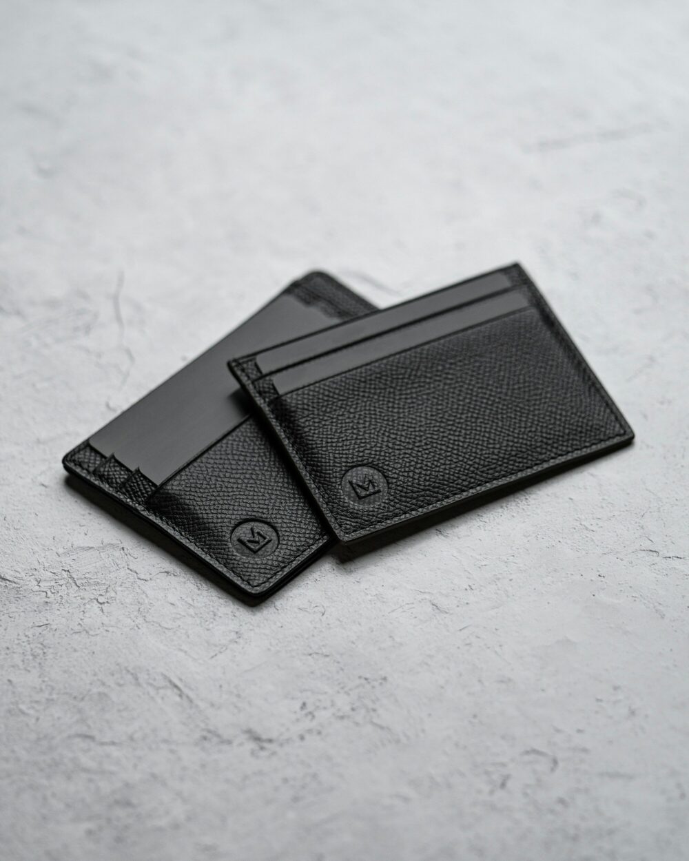 Two card holders in black on concrete