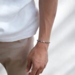 A slim silver bracelet worn on a wrist above a white tee