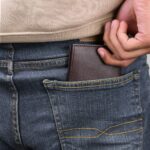 A plain leather bifold in the back pocket of a pair of jeans